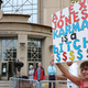 A woman holds a protest sign outside of the Waterbury Superior Court today. Alex Jones was not in attendance.
